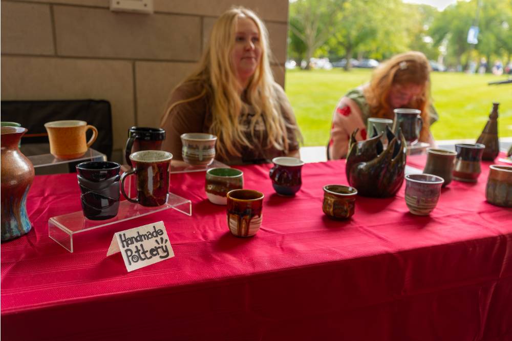 Students work a booth displaying handmade pottery at Student Small Business Market.